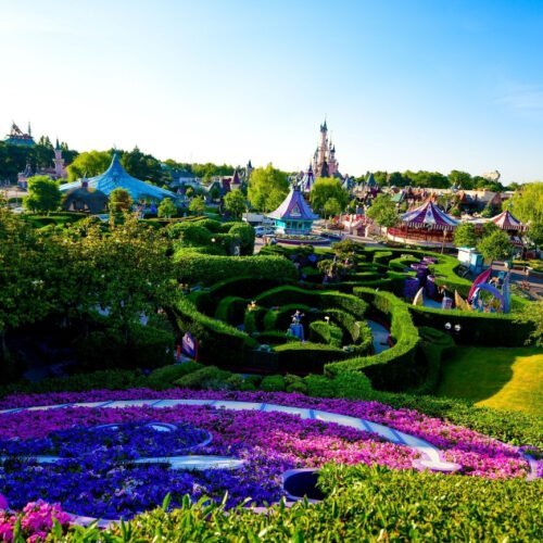 N033814 Groene heggen en roze bloemen in het doolhof van Fantasyland met uitzicht op het Kasteel