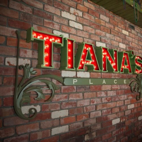 5Restaurants Entree restaurant Tiana's Place met rode letters met lampjes aan boord van de Disney Wonder