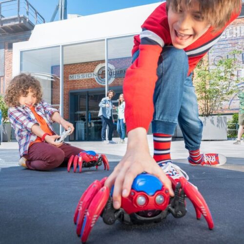 2 Kinderen spelen op straat met een rode Spider Bot