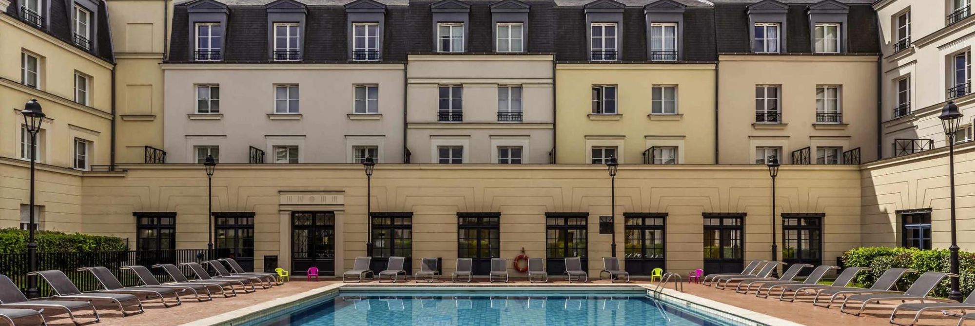 Zwembad met ligbedden op de binnenplaats van Adagio Aparthotel Serris